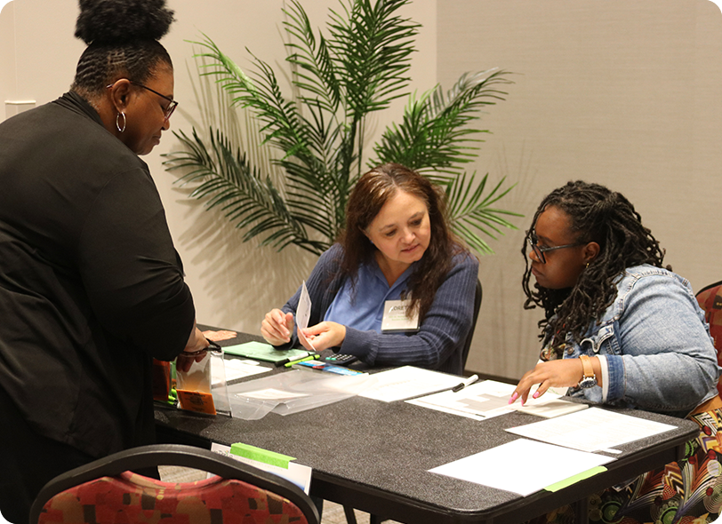 Three woman at a table looking at papers.