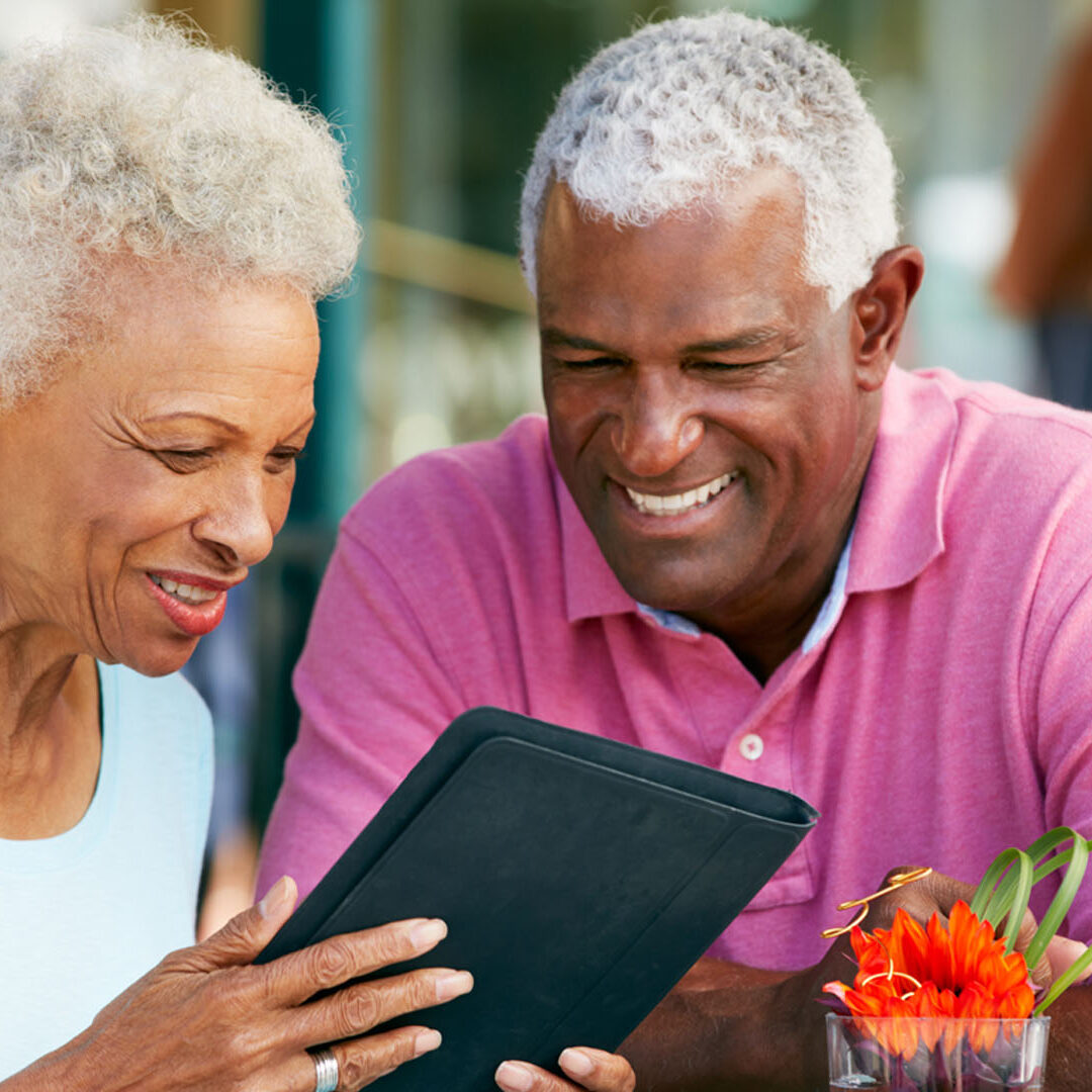 Senior Couple Using Tablet Computer At Outdoor Café